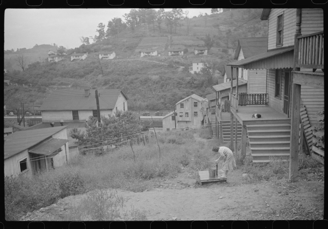 Coal miner's wife getting water from pump, company houses, Pursglove, Scotts Run, West Virginia